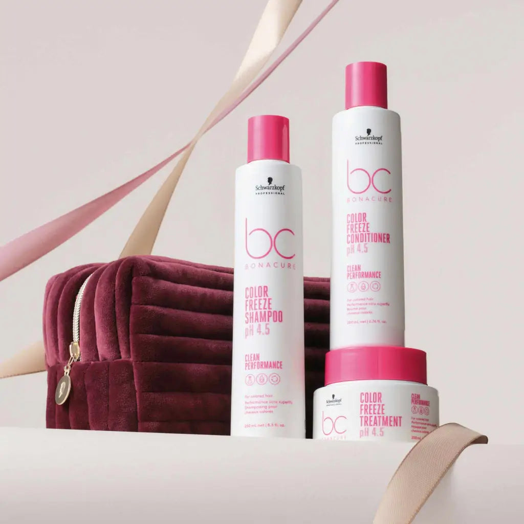 Hair care product line featuring pink and white bottles and a jar alongside a burgundy cosmetic bag.