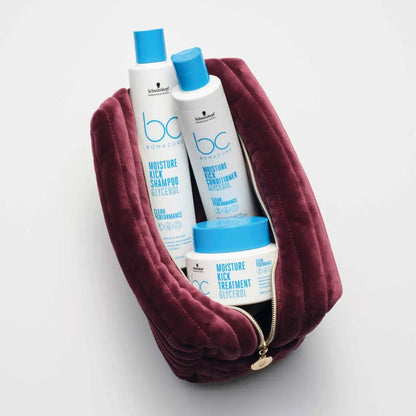 Burgundy velvet cosmetic bag containing blue and white hair care products.