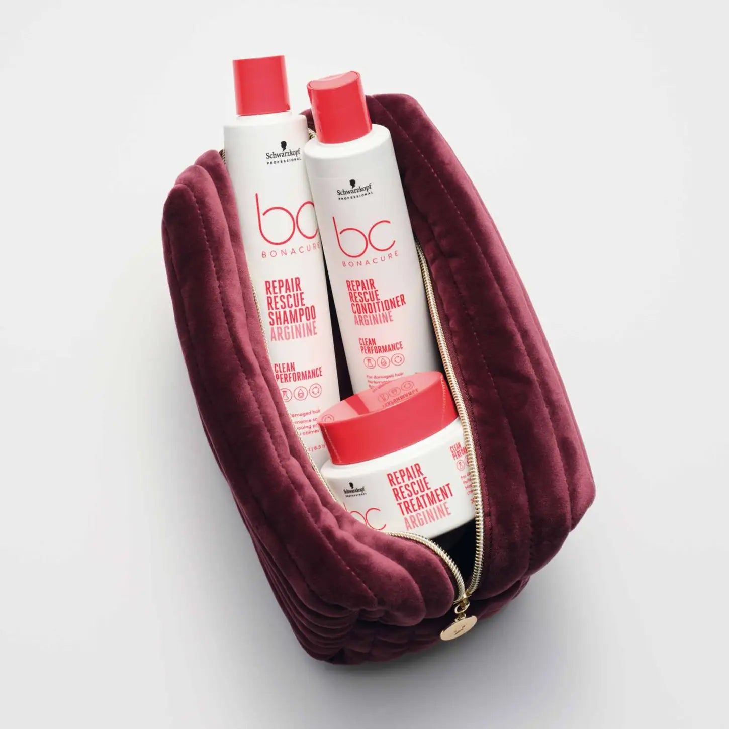 Burgundy velvet toiletry bag containing hair care products.