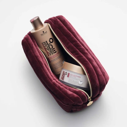 Burgundy velvet cosmetic bag with a gold zipper, partially open to reveal hair care products inside.