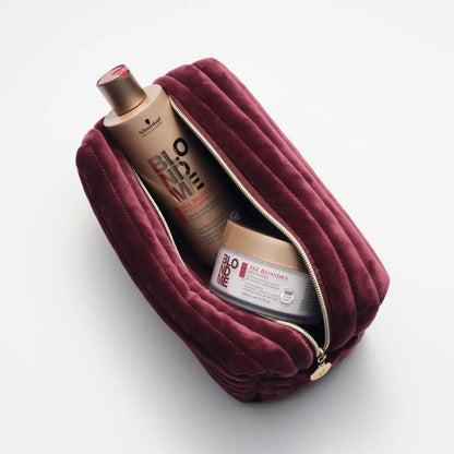 Burgundy velvet cosmetic bag or toiletry pouch containing beauty products.