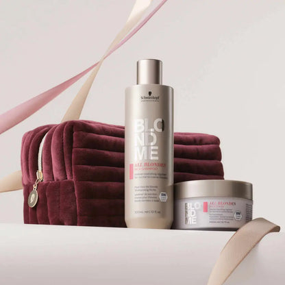 Hair care products from Schwarzkopf’s BlondMe line alongside a burgundy velvet cosmetic bag.