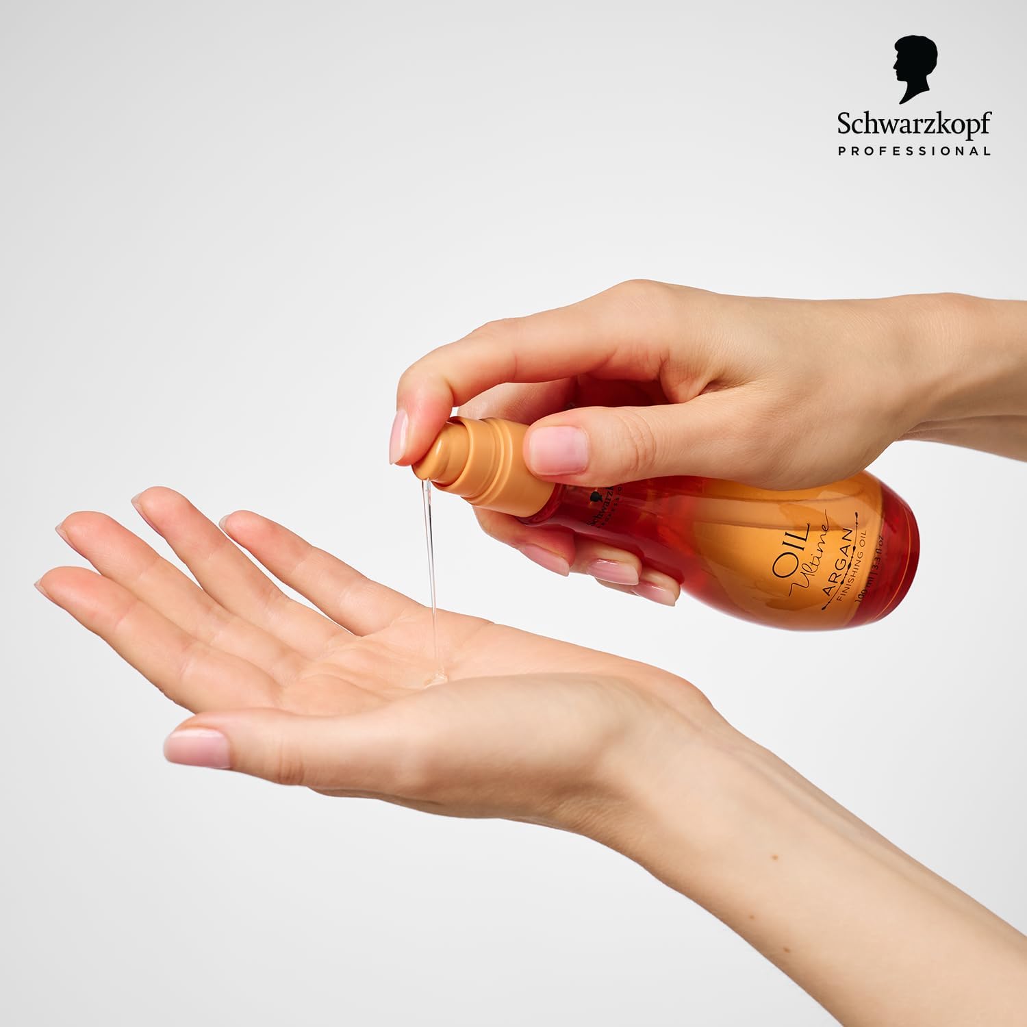 Schwarzkopf Professional Oil Ultime Argan Finishing Oil - 100ml being poured into a hand for luxurious hair care.