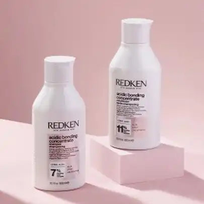 Two white bottles of Redken hair products.