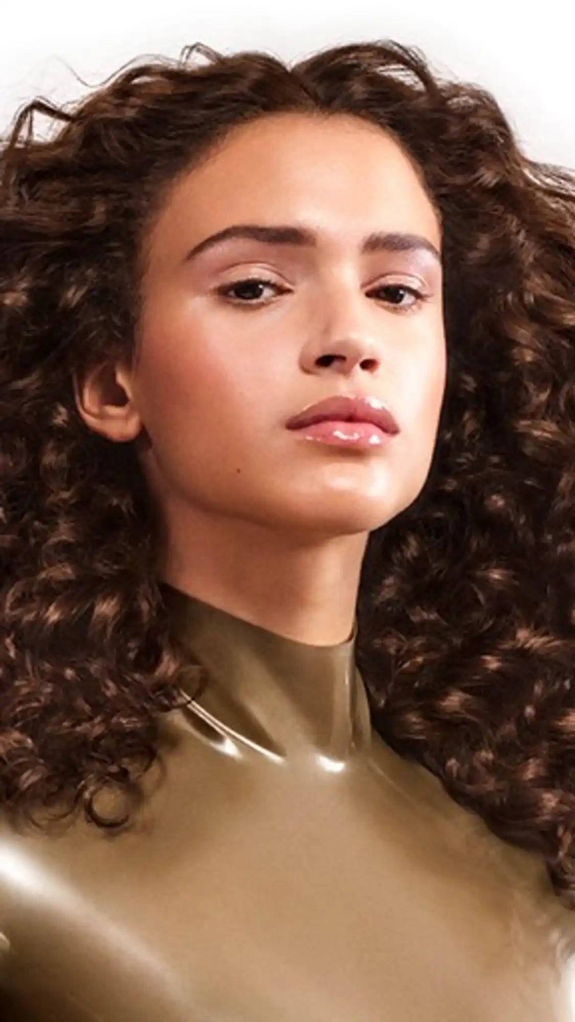 Woman with voluminous curly dark hair and a golden-hued top.